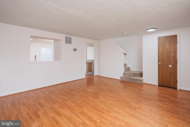 unfurnished living room with light hardwood / wood-style flooring and a textured ceiling