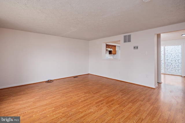 unfurnished room with a textured ceiling and light wood-type flooring