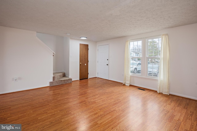 unfurnished room with a textured ceiling and light wood-type flooring