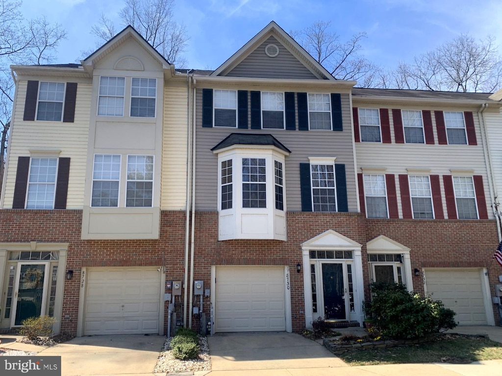 view of property with an attached garage, brick siding, and driveway