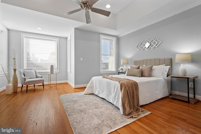 bedroom featuring multiple windows, hardwood / wood-style floors, and ceiling fan