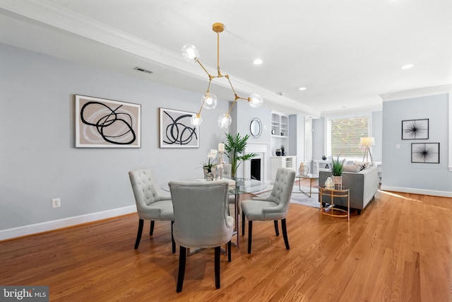 dining space featuring crown molding, built in features, and light hardwood / wood-style flooring