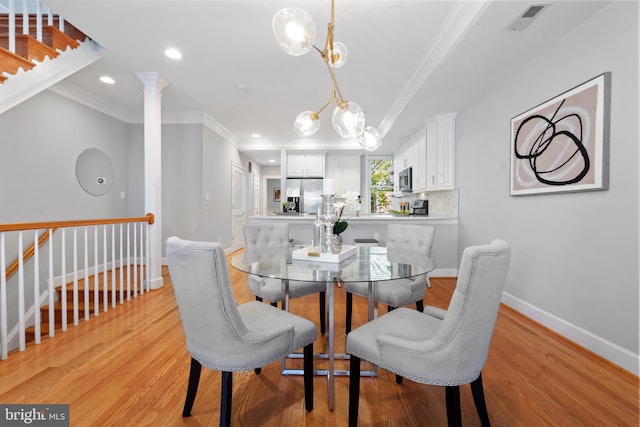 dining area featuring ornamental molding, light hardwood / wood-style floors, and decorative columns