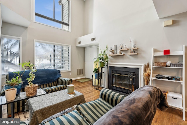 living room with a towering ceiling and light hardwood / wood-style flooring