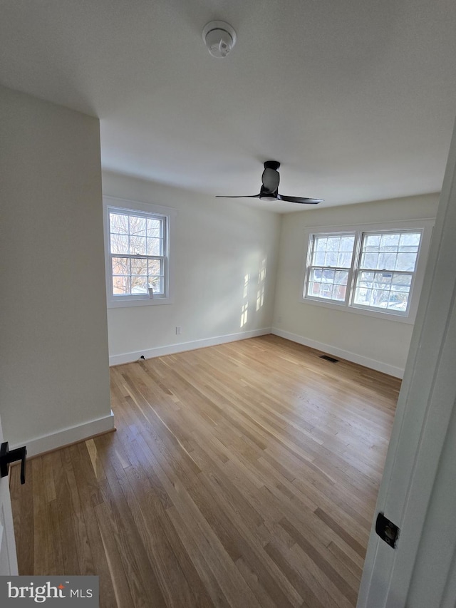 empty room with ceiling fan and light hardwood / wood-style flooring