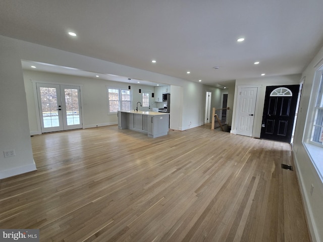 unfurnished living room featuring sink, french doors, and light wood-type flooring