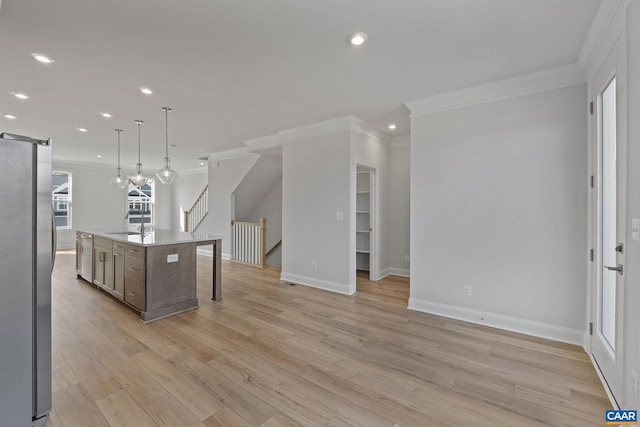 kitchen with sink, appliances with stainless steel finishes, an island with sink, decorative light fixtures, and a barn door