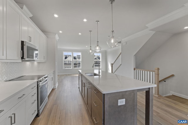 kitchen with sink, appliances with stainless steel finishes, white cabinetry, a kitchen island with sink, and decorative light fixtures