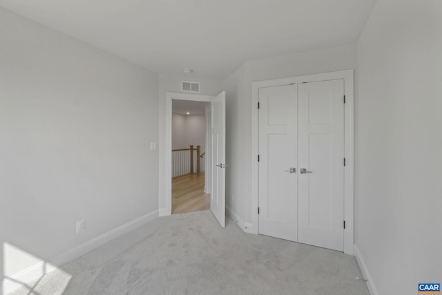 unfurnished bedroom featuring light carpet and a closet