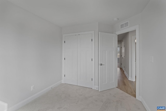 unfurnished bedroom featuring light carpet and a closet