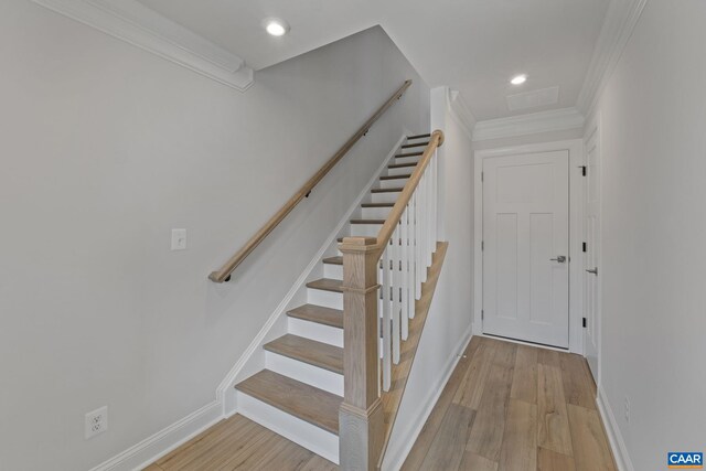 staircase with crown molding and wood-type flooring