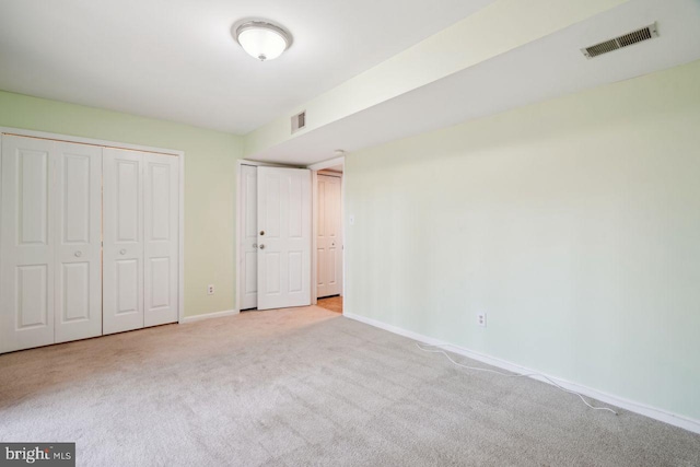 unfurnished bedroom with light carpet and multiple closets