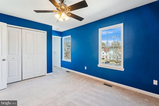 unfurnished bedroom featuring ceiling fan, a closet, and light carpet