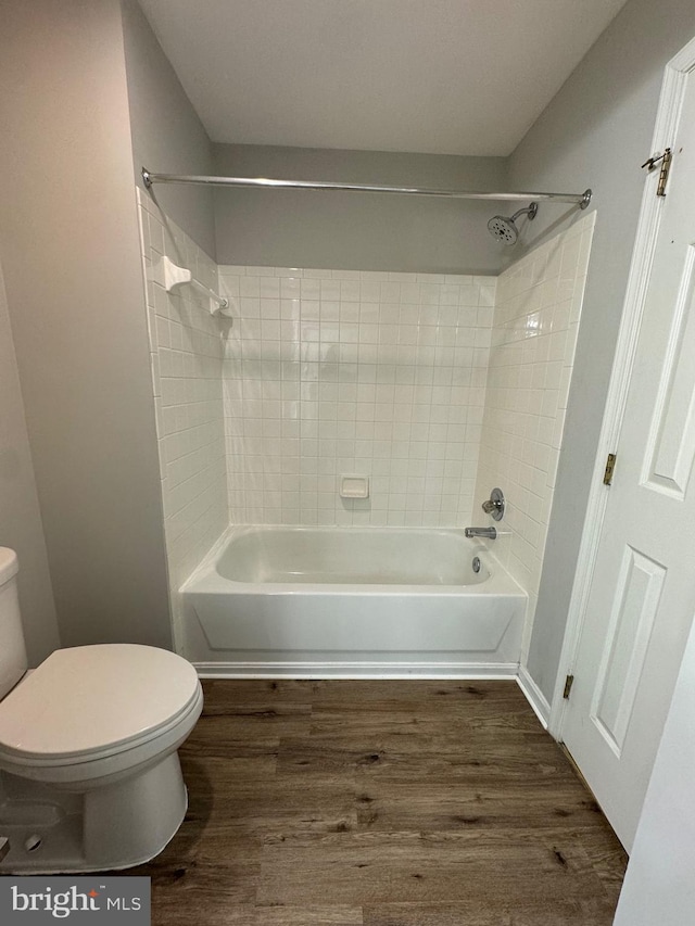 bathroom featuring tiled shower / bath, hardwood / wood-style flooring, and toilet