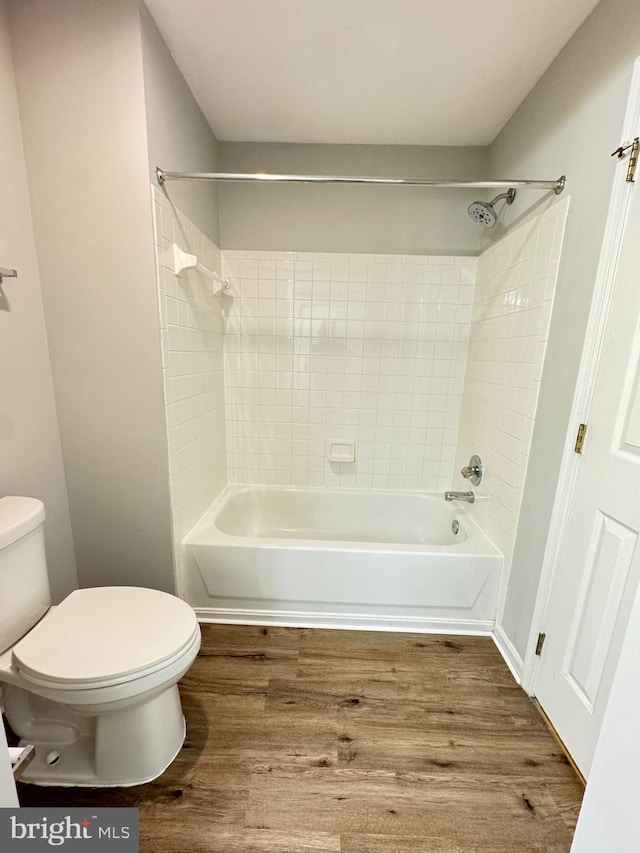 bathroom with tiled shower / bath combo, hardwood / wood-style floors, and toilet