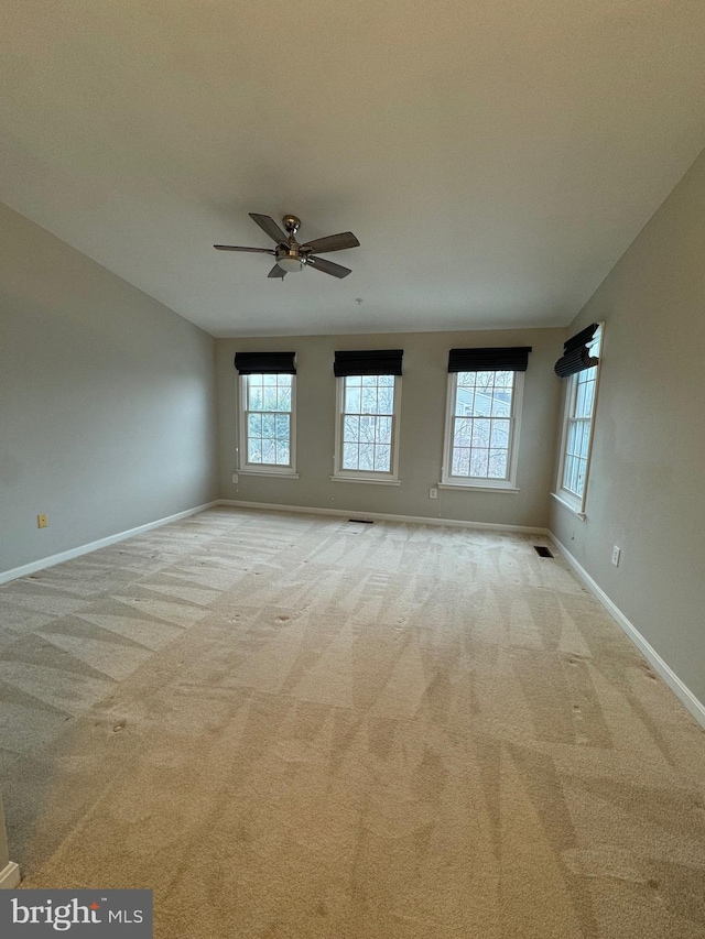 empty room featuring ceiling fan and light carpet