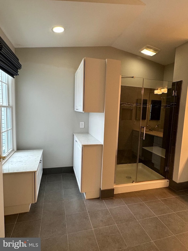 bathroom featuring lofted ceiling, tile patterned floors, and a shower with door