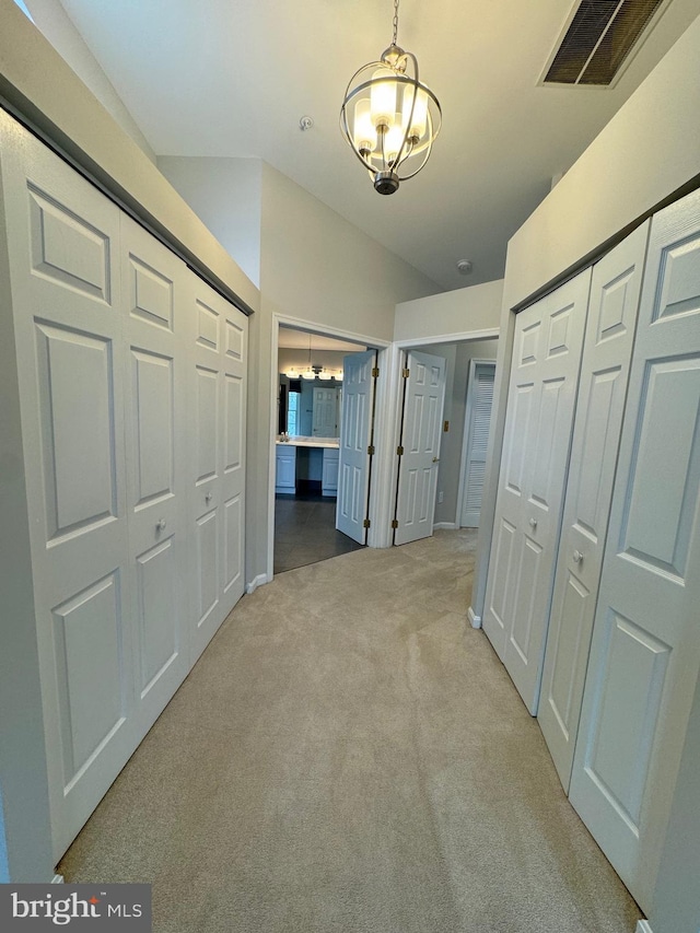 hallway with light colored carpet and lofted ceiling