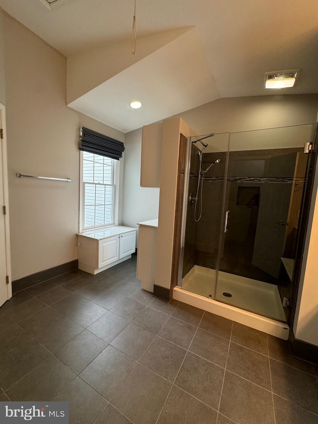 bathroom featuring tile patterned flooring, vanity, lofted ceiling, and walk in shower