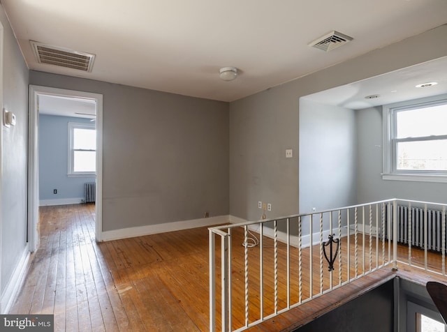 hallway with radiator and hardwood / wood-style floors