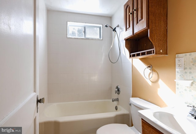 full bathroom featuring tiled shower / bath, vanity, and toilet