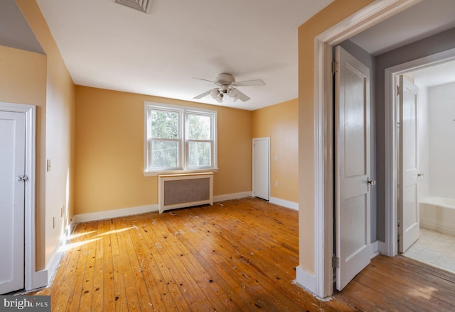 spare room featuring ceiling fan, radiator, and light wood-type flooring