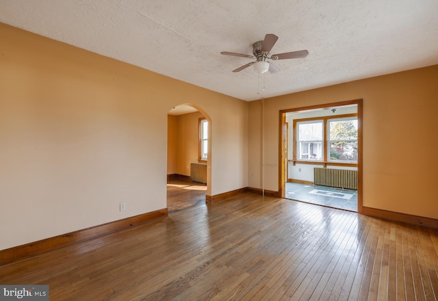 spare room with radiator, hardwood / wood-style floors, a textured ceiling, and ceiling fan