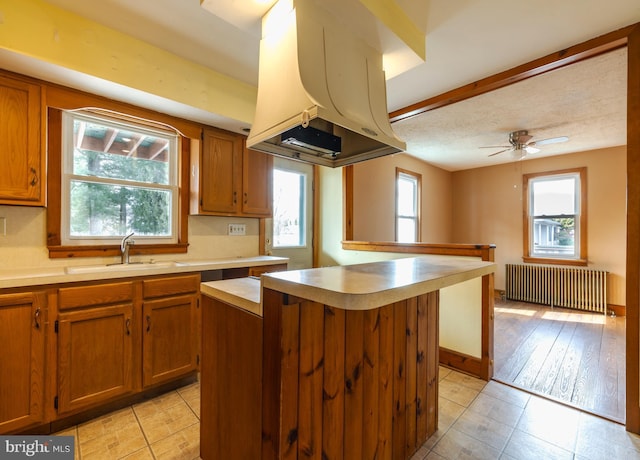 kitchen with a center island, island range hood, radiator, and sink