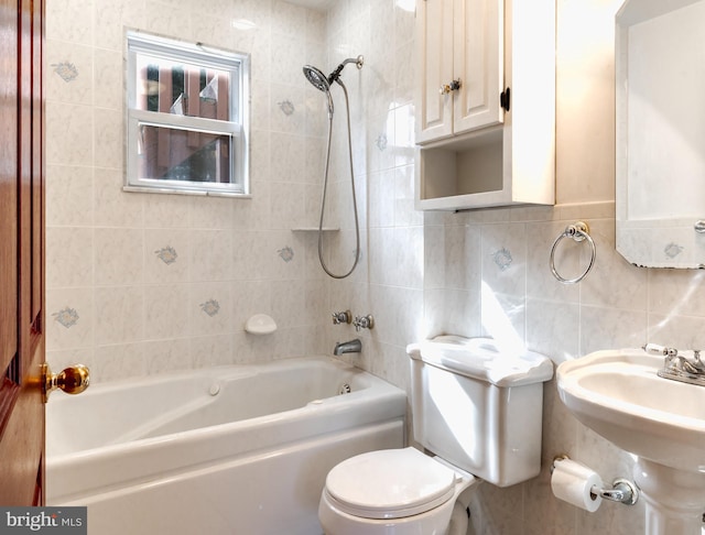 full bathroom featuring tiled shower / bath, sink, tile walls, and toilet