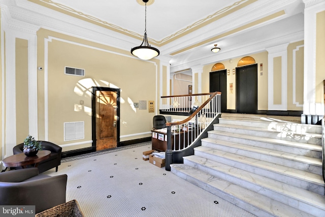 foyer featuring ornamental molding, elevator, and ornate columns