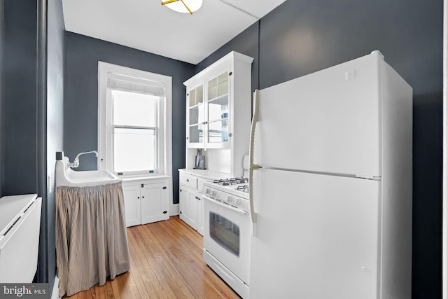 kitchen featuring sink, white appliances, light hardwood / wood-style flooring, and white cabinets