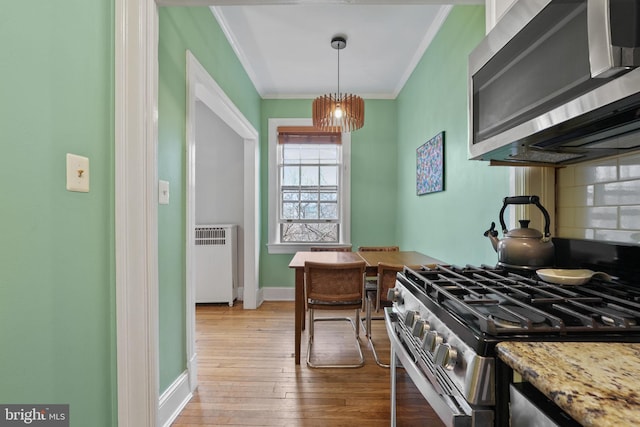 kitchen featuring radiator heating unit, tasteful backsplash, hanging light fixtures, ornamental molding, and stainless steel appliances