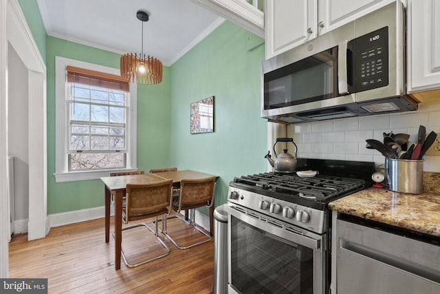 kitchen with light stone counters, stainless steel appliances, crown molding, and white cabinets