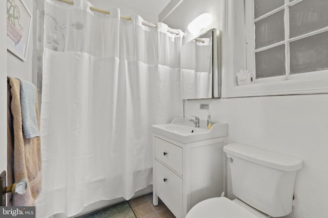 bathroom with tile patterned flooring, vanity, walk in shower, and toilet