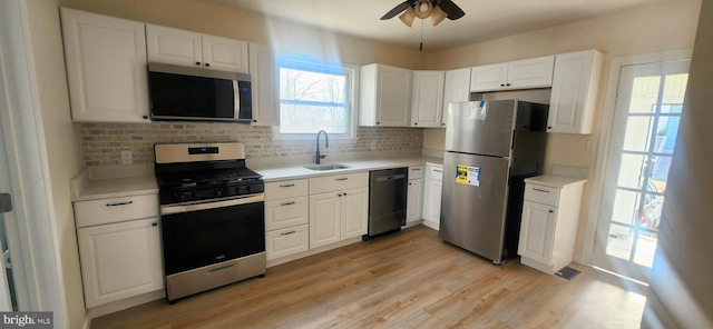 kitchen with sink, light hardwood / wood-style flooring, white cabinetry, backsplash, and stainless steel appliances