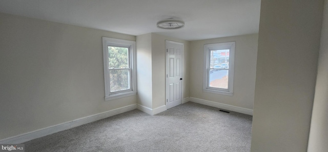 empty room featuring light colored carpet and a healthy amount of sunlight