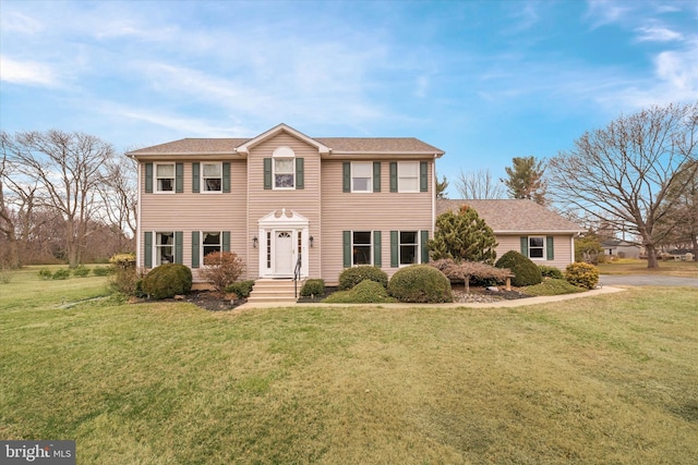 colonial inspired home featuring a front yard and a shingled roof