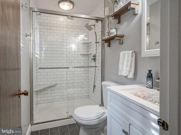 bathroom featuring vanity, tile patterned flooring, a shower with shower door, and toilet