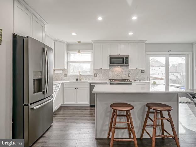 kitchen featuring stainless steel appliances, a kitchen island, sink, and hanging light fixtures