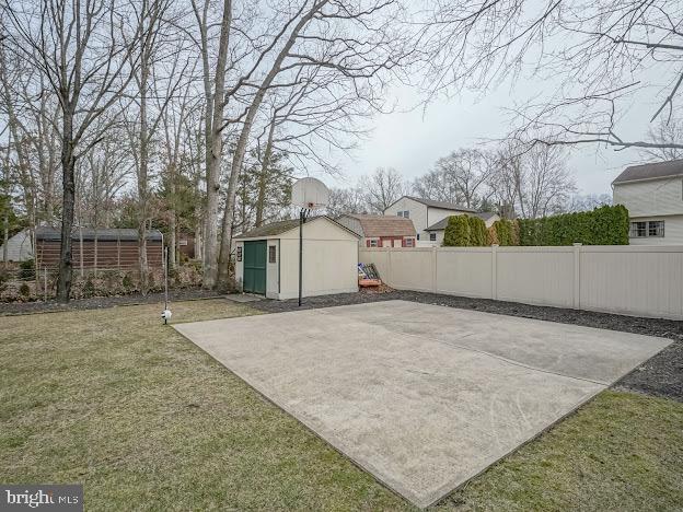 view of patio / terrace featuring basketball hoop and a storage unit