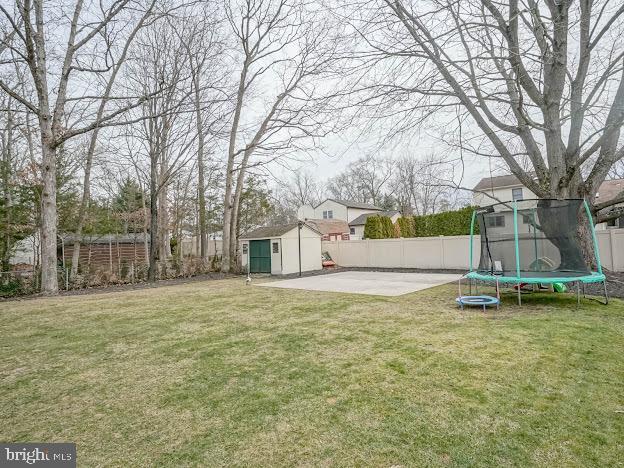 view of yard with a patio area, a trampoline, and a storage unit