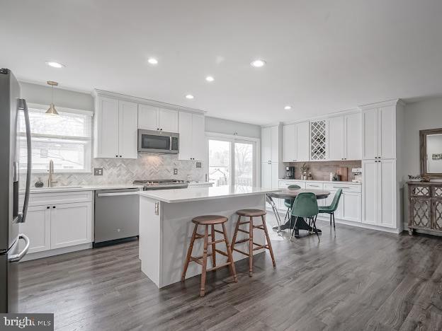 kitchen with pendant lighting, appliances with stainless steel finishes, a kitchen island, and white cabinets