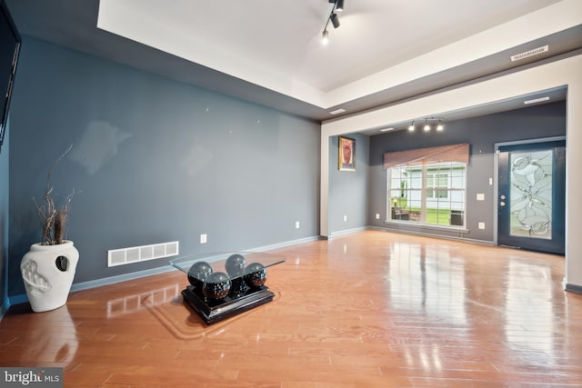 exercise area featuring hardwood / wood-style flooring and track lighting