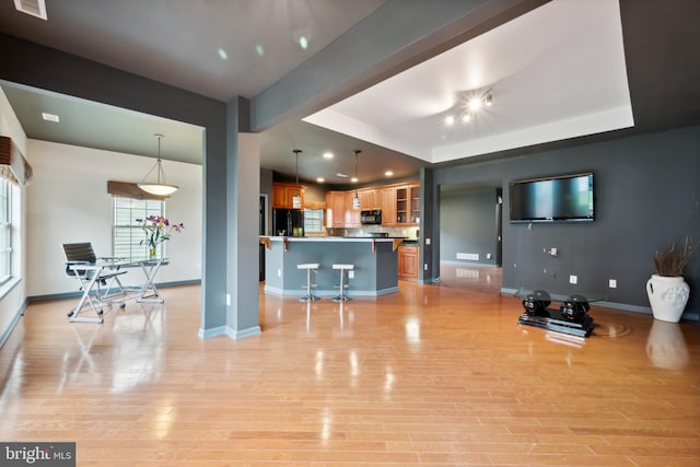 living room featuring a tray ceiling and light hardwood / wood-style floors