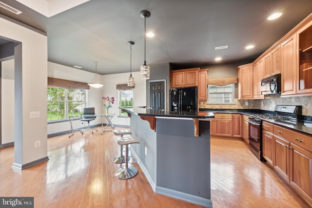 kitchen featuring a kitchen island, tasteful backsplash, a kitchen breakfast bar, hanging light fixtures, and black appliances