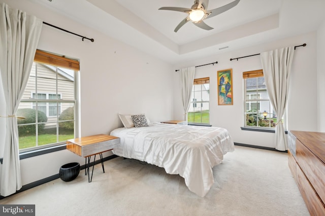 bedroom featuring light colored carpet, ceiling fan, and a tray ceiling