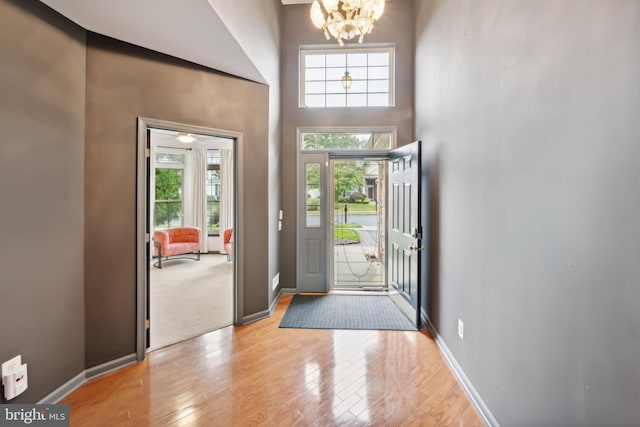 entryway featuring light hardwood / wood-style flooring, a wealth of natural light, a chandelier, and a high ceiling