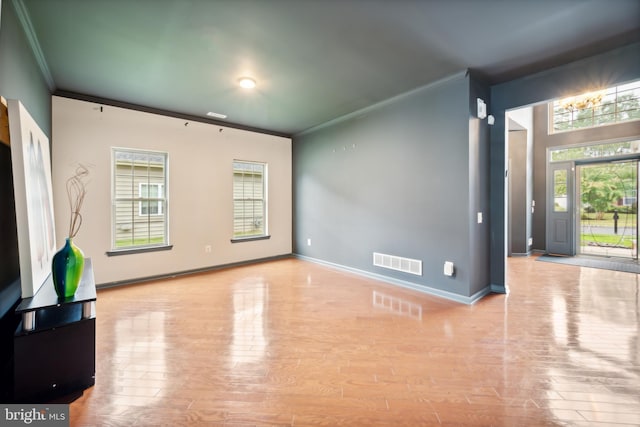 unfurnished living room featuring ornamental molding and light wood-type flooring