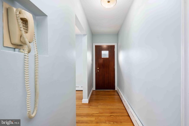 doorway with a baseboard heating unit, baseboards, baseboard heating, and wood finished floors