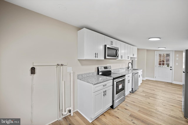 kitchen with sink, white cabinetry, stainless steel appliances, light stone countertops, and light hardwood / wood-style floors